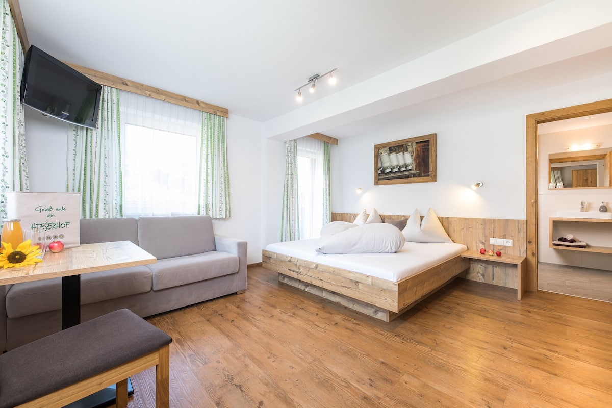 A modern bedroom with a bed, a sofa, a table, and a TV.
