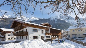 A snow-covered mountain village with wooden buildings and a large snow pile. - Hieserhof (Neustift Im Stubaital)