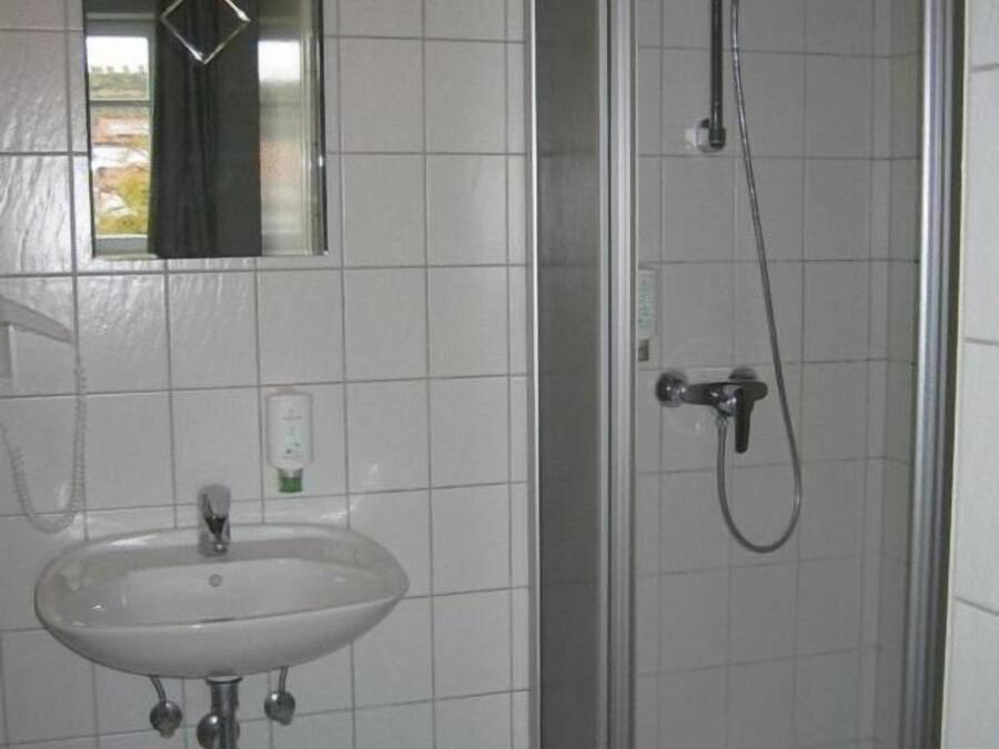 Un baño con un lavabo blanco, un espejo y cabina de ducha con paredes de vidrio.