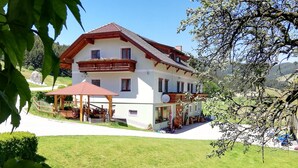 Ein zweistöckiges Haus mit Balkon, überdachter Terrasse und Garage mit geparkten Fahrzeugen.
