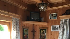 Un interior de madera con una mesa de comedor, sillas, un televisor y cuadros en las paredes.