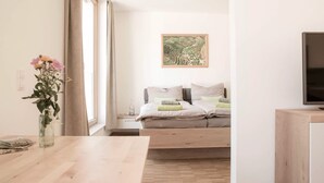 Une chambre moderne avec un lit, une télévision, une table en bois et une fenêtre avec des rideaux.