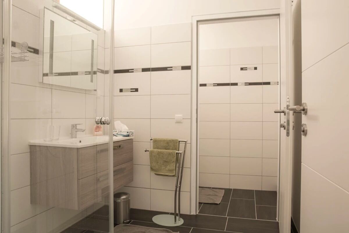 Un baño moderno con cabina de ducha de vidrio, un lavabo blanco y un perchero para toallas.