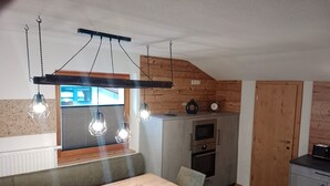 Una cocina moderna con una pared de acento de madera, luces colgantes, electrodomésticos integrados y un comedor con banco.