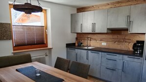 Una cocina moderna con armarios grises, encimera de madera y una ventana con persianas.