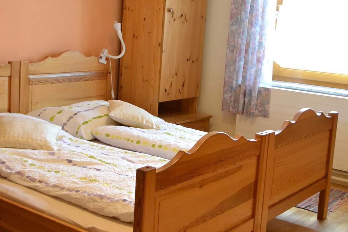 A wooden bed with a headboard, a wooden wardrobe, and a window with curtains.