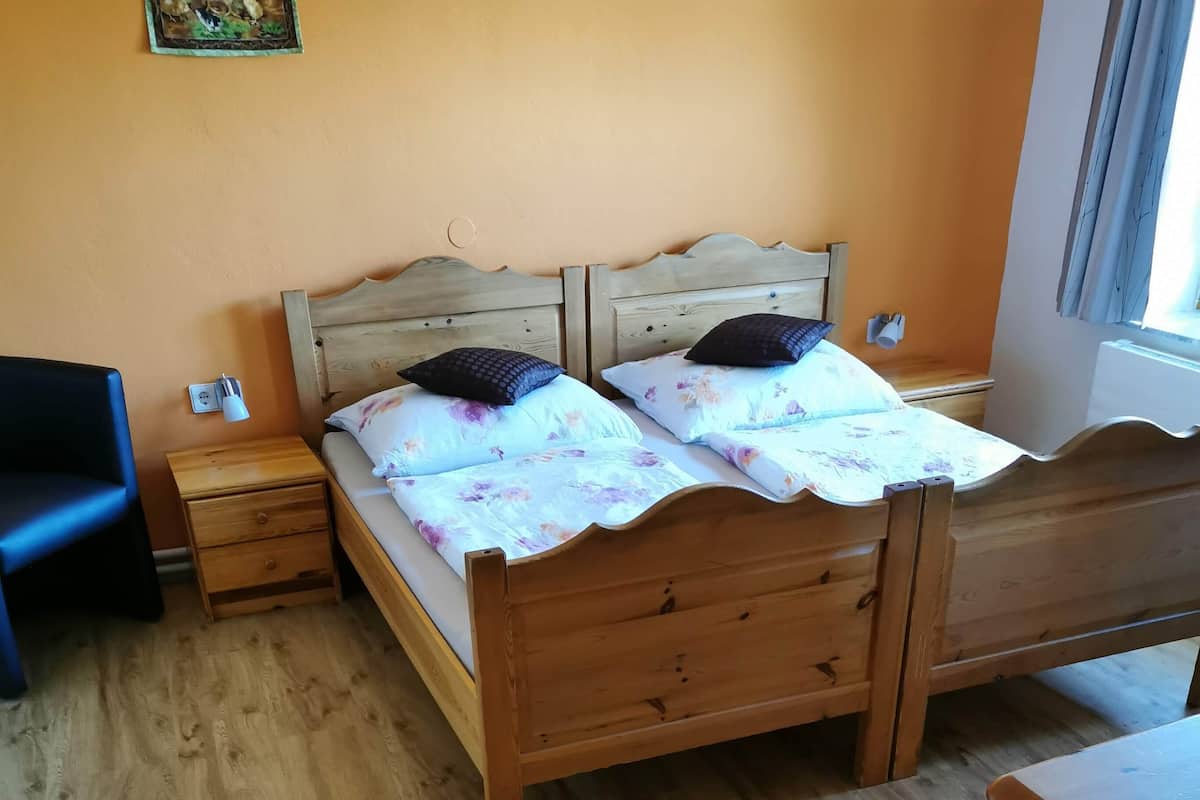 A wooden bed with a headboard, two bedside tables, a nightstand, and a desk.