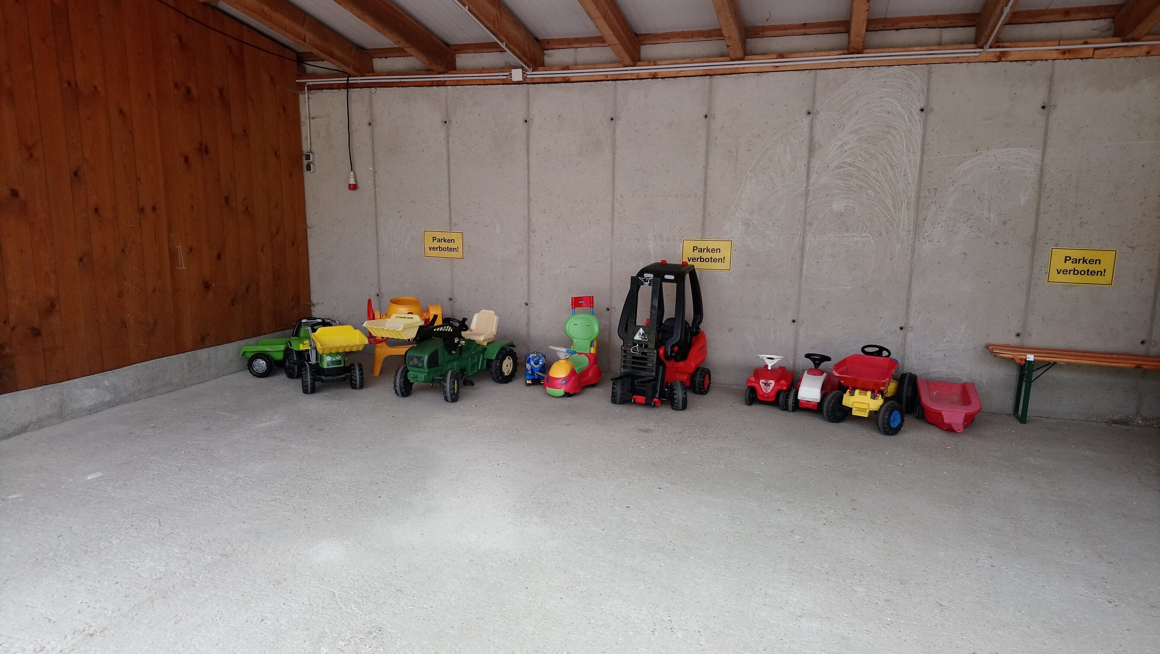 A garage with toy vehicles and a wooden bench.