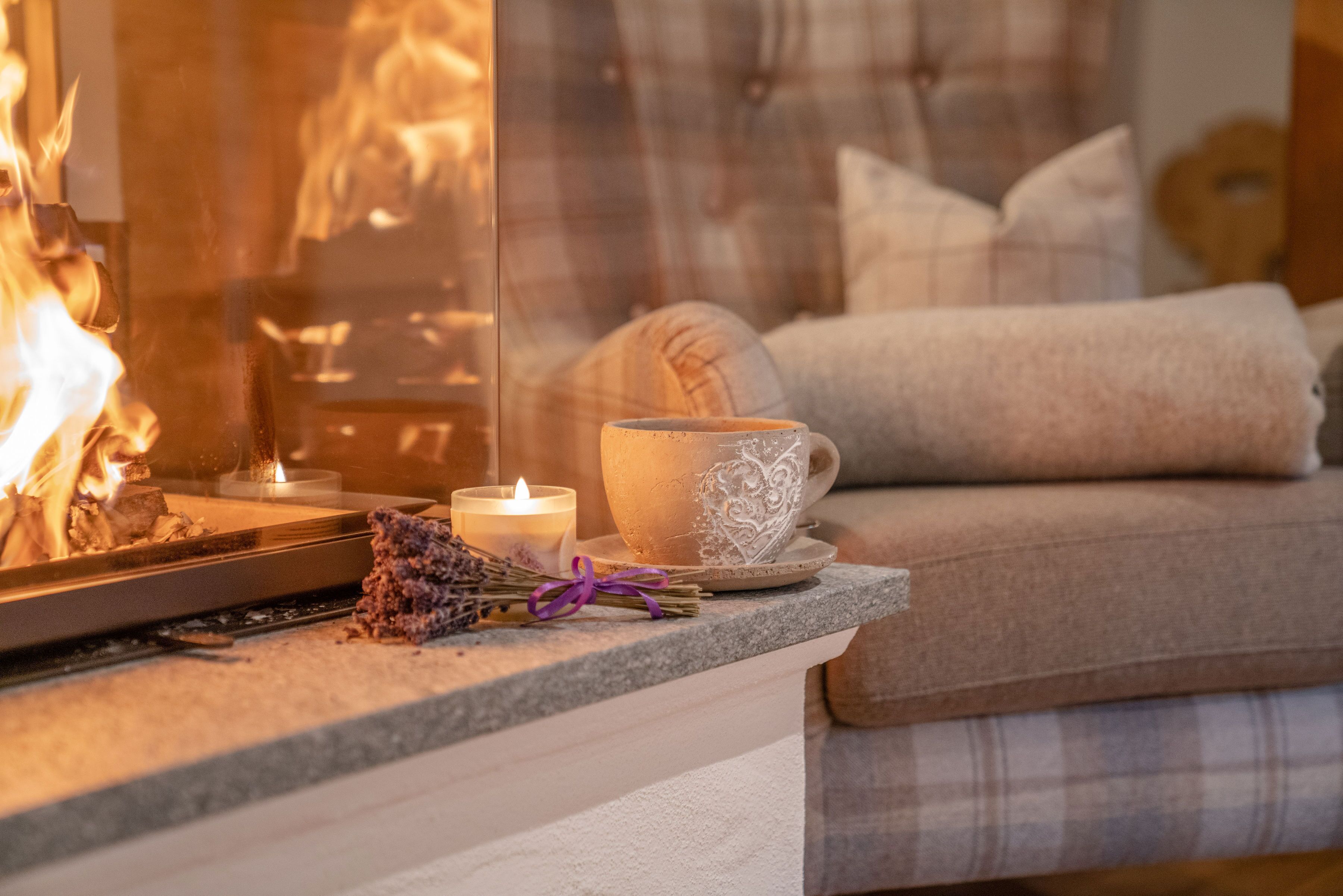 A cozy living area with a fireplace, a cup with a heart design, and a candle on a table.