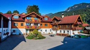 A traditional wooden building with balconies, a central courtyard, and a mountain backdrop. - Linharterhof Zimmer (Haus)