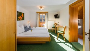 A hotel room with two beds, a desk, a chair, a TV, and a window with curtains. - Linharterhof Zimmer (Haus)