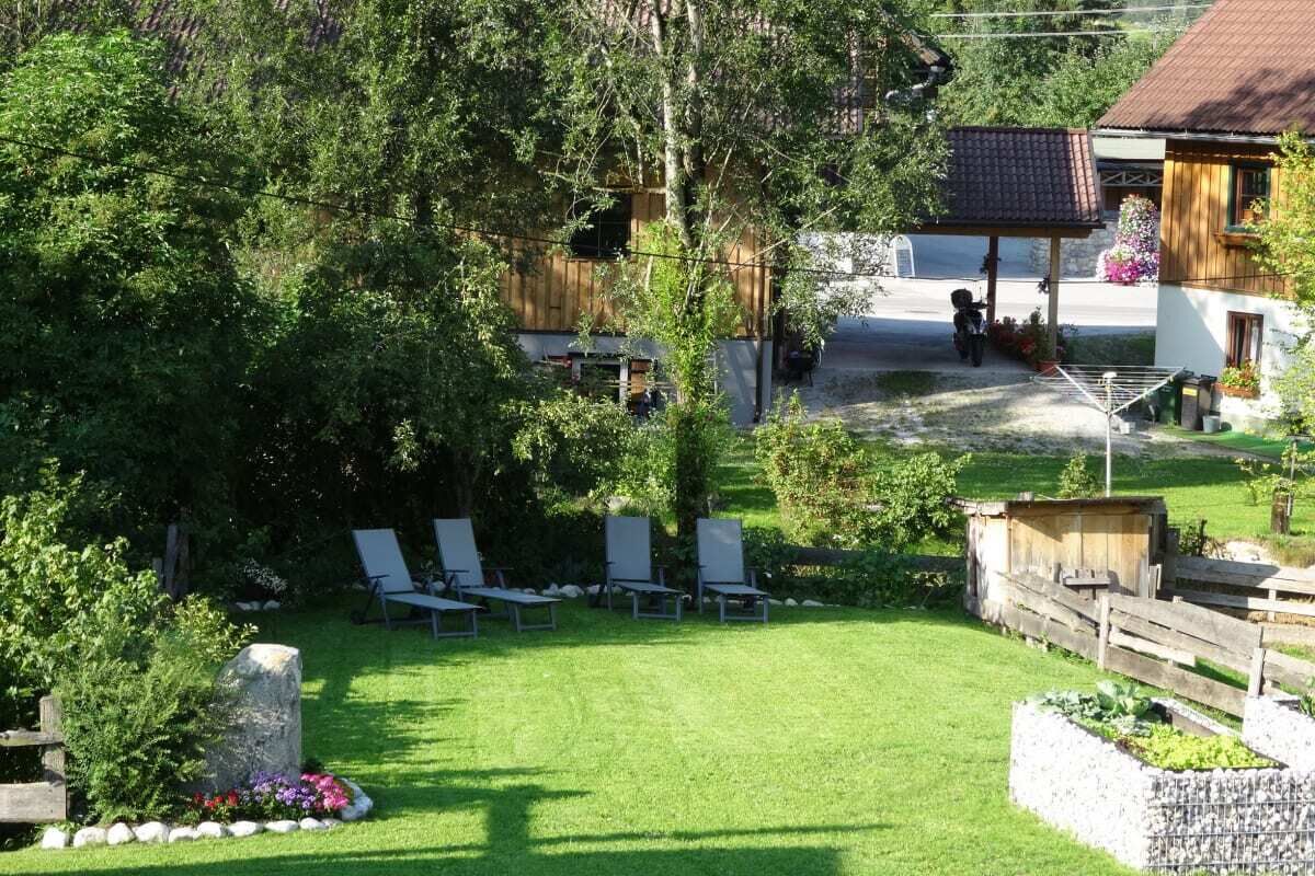 Ländliche Szenerie mit Rasen, Sitzgelegenheiten im Freien und einer Holzhütte.