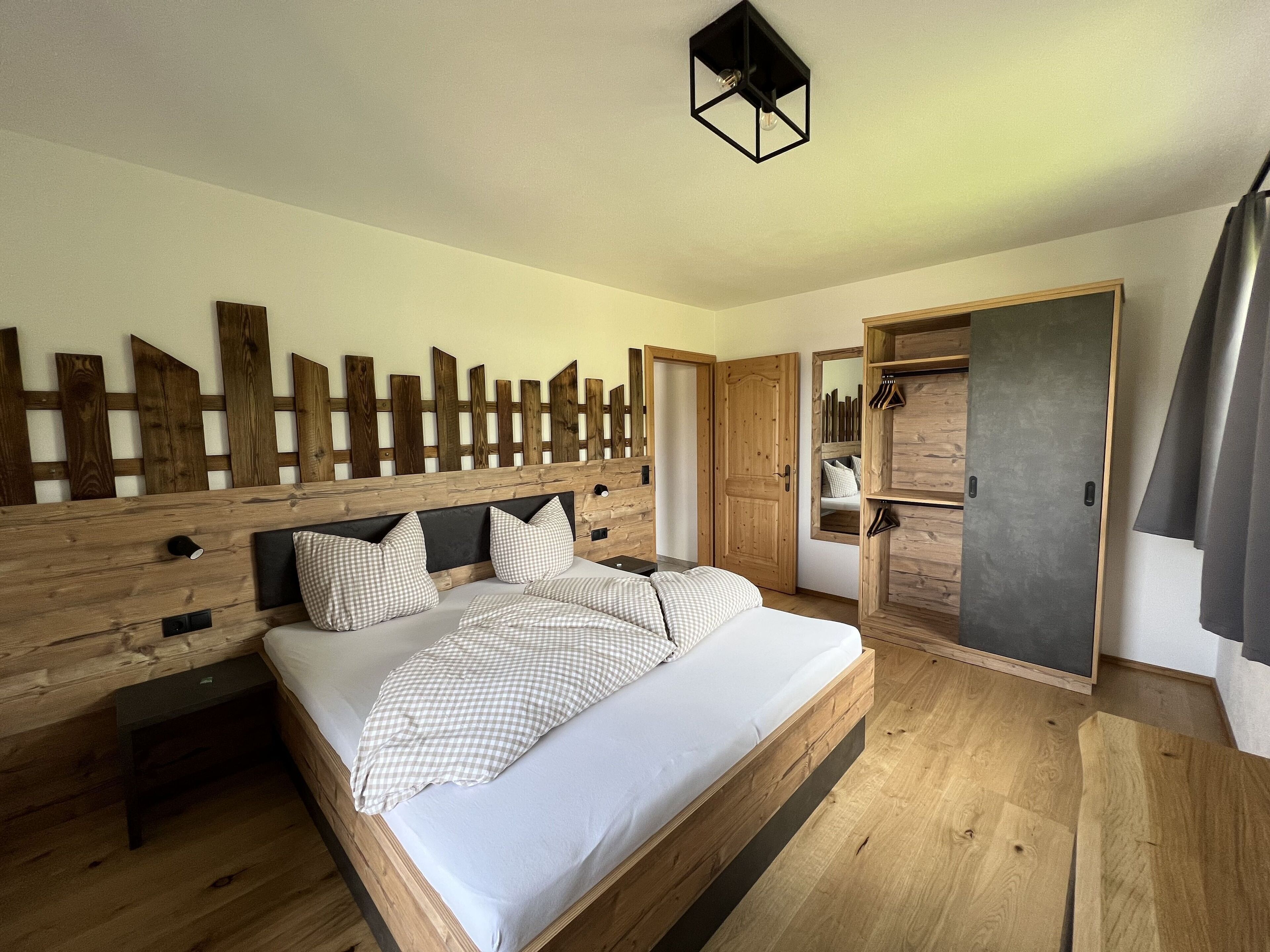 A wooden bed with a headboard, a bedside table, and a wardrobe with a mirror.