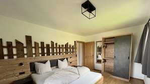 A wooden bed with a headboard, a bedside table, and a wardrobe with a mirror. - Studlerhof (Oberperfuss)