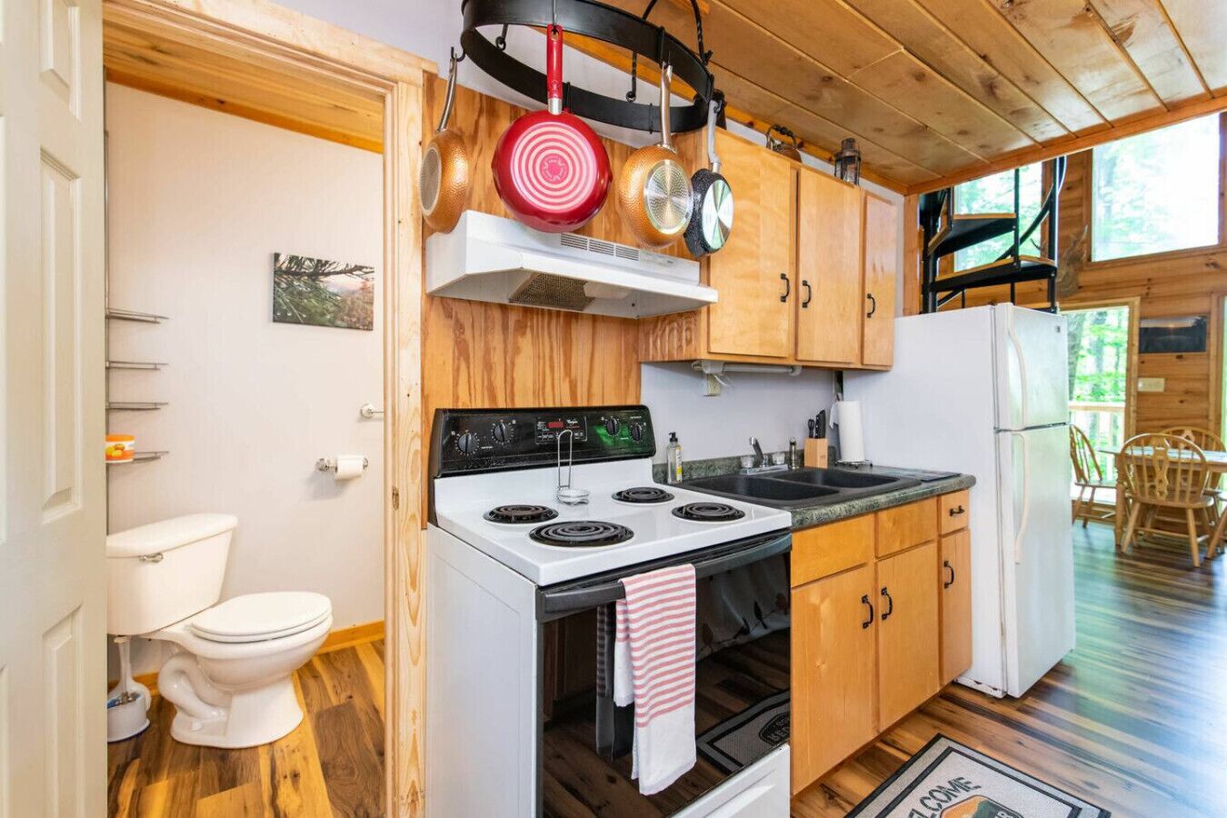 Una cocina compacta con estufa, pileta y refrigerador, muebles de madera y ventana con vista a una terraza.