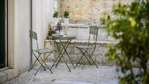 A small outdoor seating area with a table and two chairs, surrounded by stone walls and potted plants. - Apartments Franka Old Town (Dubrovnik)