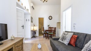 A living room with a sofa, coffee table, TV, and a dining area with chairs and a table. - Apartments Franka Old Town (Dubrovnik)