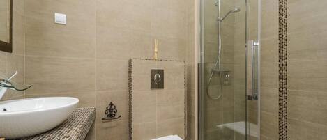 A bathroom with a large sink, toilet, and glass-enclosed shower.