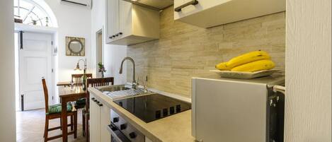 Eine moderne Küche mit Einbauofen, Kühlschrank und Spüle. Im Hintergrund ist ein Essbereich mit Tisch und Stühlen zu sehen.