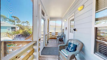 Relax on the covered porch with a view of the surrounding landscape, featuring a comfortable seating area with wicker chairs and a small table.
