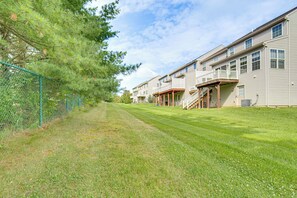 A residential building with a front porch, a fenced yard, and a clear sky. - Charming Bellefonte Townhome Near Penn State! (Bellefonte)