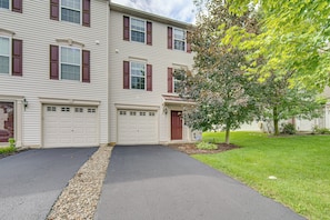 A two-story residential building with a garage, a front door, and a driveway. - Charming Bellefonte Townhome Near Penn State! (Bellefonte)