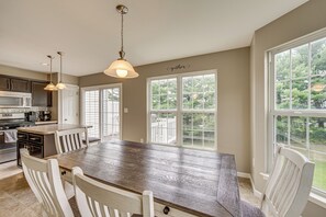 Una cocina amplia con una isla grande, muebles blancos y vistas al exterior gracias a amplias ventanas.