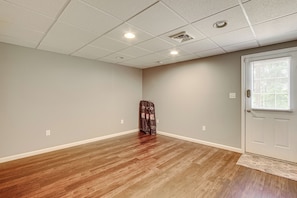 A room with a wooden floor, a white door, and a window with blinds. - Charming Bellefonte Townhome Near Penn State! (Bellefonte)