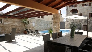 Un patio al aire libre con piscina, mobiliario de mimbre y paredes de piedra.