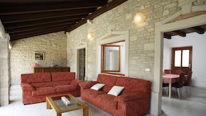 Amplia sala de estar con un sofá rojo, una mesa de centro de madera y una pared de piedra.