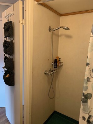 A small bathroom with a shower, a towel rack with multiple towels, and a toilet paper holder.