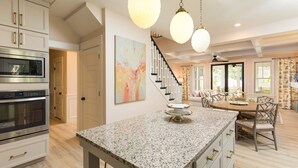 A kitchen with granite countertops, stainless steel appliances, and a dining area with a wooden table and chairs. - Tuck'd Away - Newly Built Vacation Home Located in Downtown Saugatuck (Saugatuck)