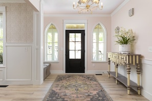 Stunning hallway with a patterned rug and arched windows leading to a black door.
