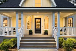 Traditional two-story home with a symmetrical facade, featuring a black door and arched windows.
