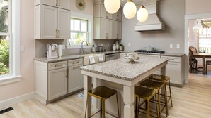 A kitchen with white cabinets, a granite countertop, and gold bar stools. - Tuck'd Away - Newly Built Vacation Home Located in Downtown Saugatuck (Saugatuck)