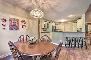 Enjoy meals in this cozy dining area with a round table and six chairs, surrounded by decorative items and a chandelier.