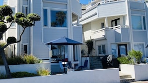 Ein modernes, mehrgeschossiges Gebäude mit großen Fenstern, Außenbestuhlung und einer überdachten Terrassenfläche.