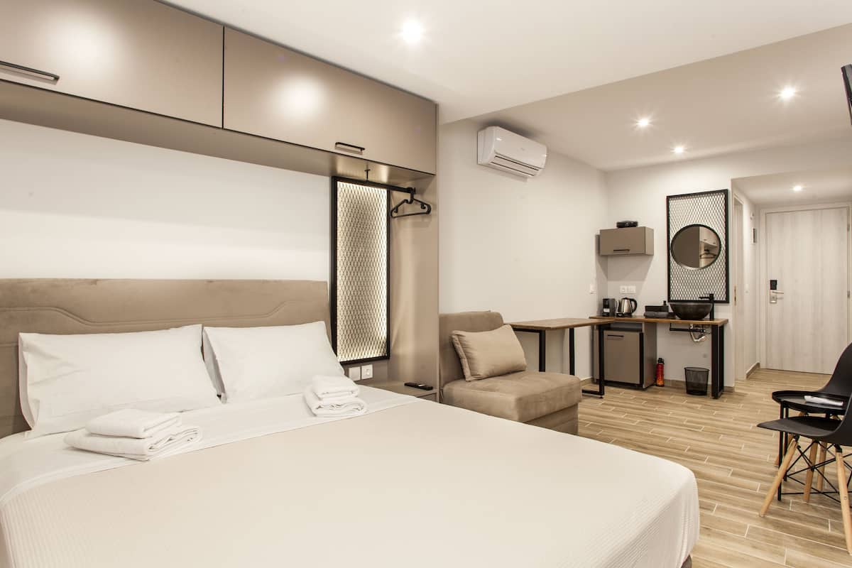Ein modernes Hotelzimmer mit einem großen Bett, einem Schreibtisch, einem Stuhl und einer Küchenzeile.