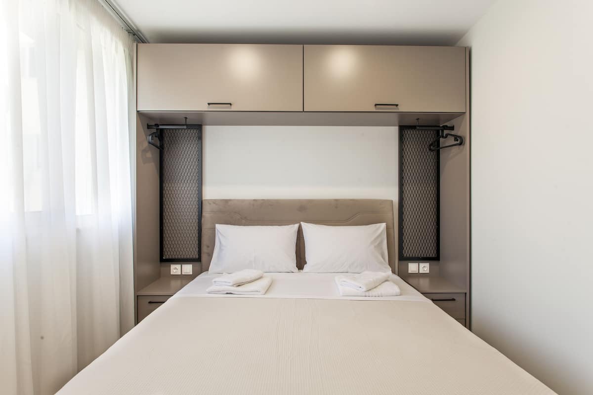 Ein modernes Hotelzimmer mit einem großen Bett, zwei Nachttischen und einem Kopfteil mit integrierter Beleuchtung.