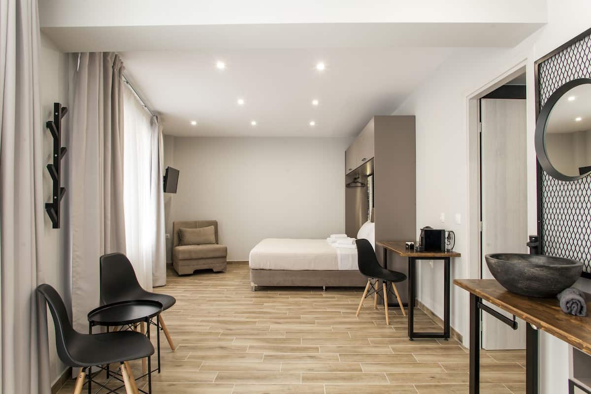 Ein modernes Hotelzimmer mit einem Bett, einem Schreibtisch mit einer Schale, zwei St ühlen, einem Sofa und einem Spiegel.