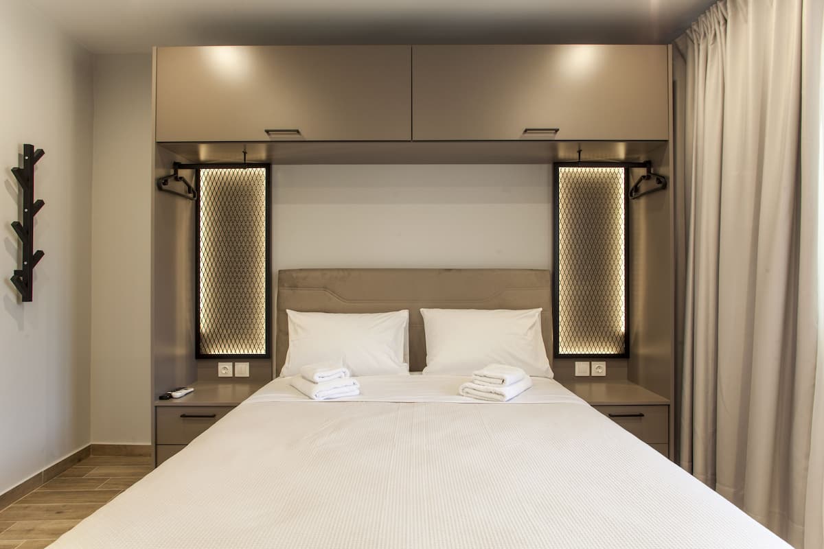 Ein modernes Hotelzimmer mit einem großen Bett, zwei Nachttischen, einem Kleiderschrank und einem Spiegel mit Netzmuster.