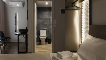 A modern hotel room with a bed, a desk, and a bathroom visible through an open door.