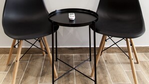 A room with two black chairs, a small round table, and a large mirror on the wall. - Raise The Heraklion Project (Heraklion)
