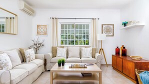 A living room with a beige sofa, a wooden coffee table, and a window with curtains.