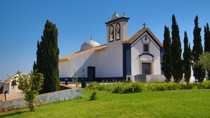 A church with a bell tower, surrounded by cypress trees and a well-maintained lawn.