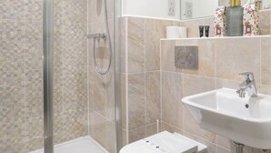 A modern bathroom with a glass-enclosed shower, a white sink, and a toilet. - Tudors eSuites Apartment with 4 Beds (Birmingham)