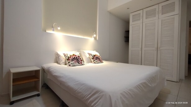 Ein modernes Schlafzimmer mit einem großen Bett, zwei Nachttischlampen, einem Nachttisch und einem Kleiderschrank.