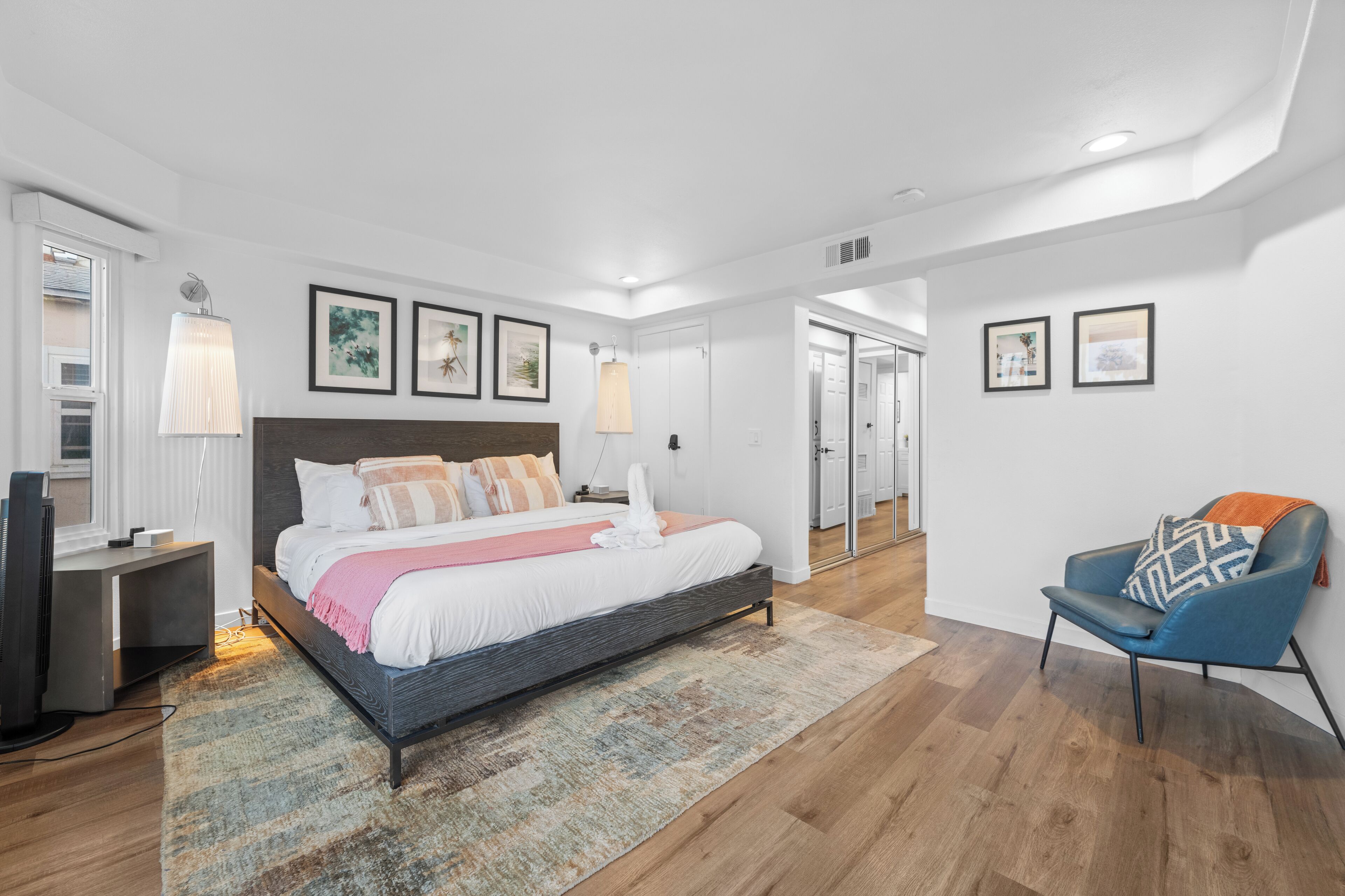 A modern bedroom with a large bed, bedside lamps, a flat-screen TV, and a chair.