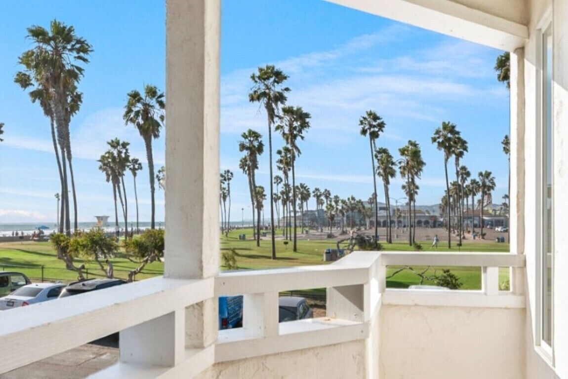 Ein Balkon mit Blick auf Palmen und eine Rasenfläche.