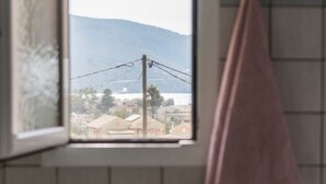A bathroom with a window, a pink towel, and tiled walls.